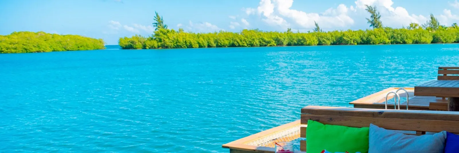 Low mangrove islands on calm turquoise water beside the resort's wooden deck.