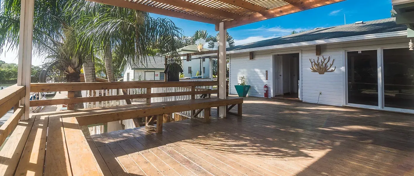 A wide wooden deck under a pergola beside the resort buildings.