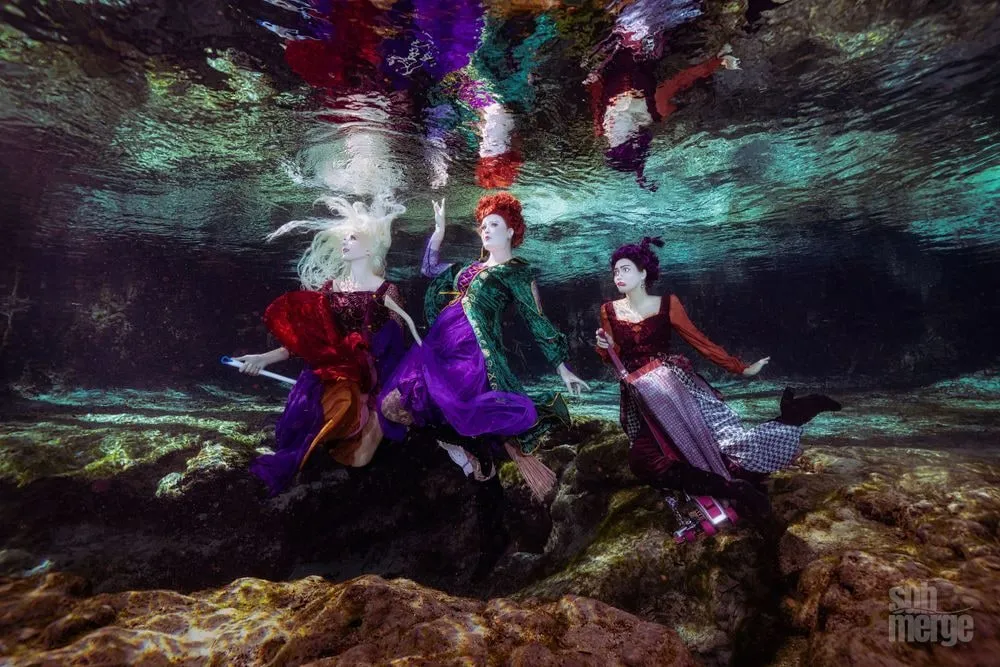Three models costumed as the Sanderson sisters from Hocus Pocus pose underwater on the rocky floor of a Florida spring.